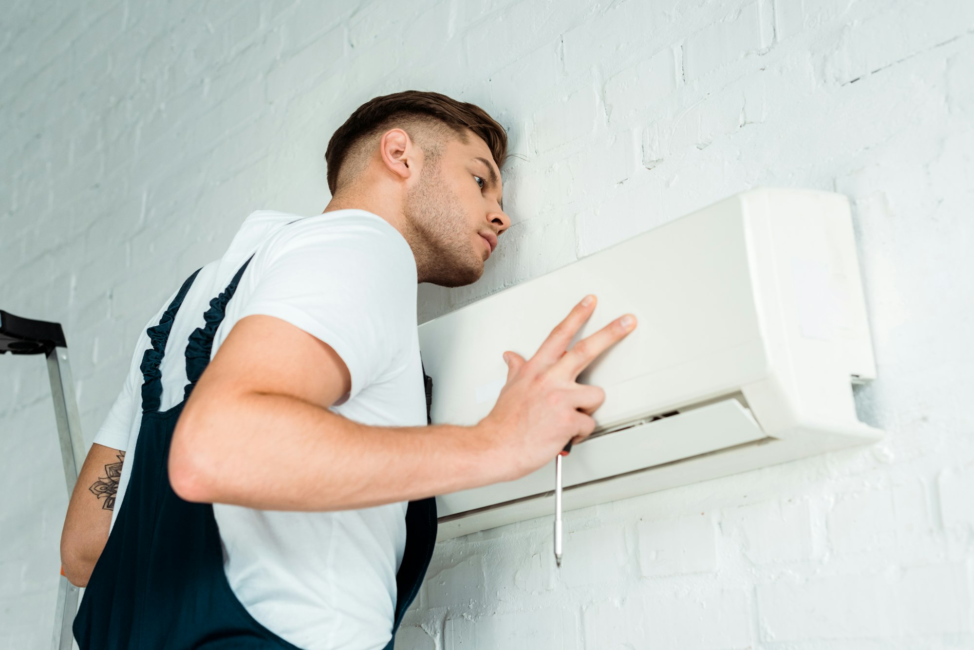 Trabajador instalando un aire acondicionado para un sistema de climatización eficiente.