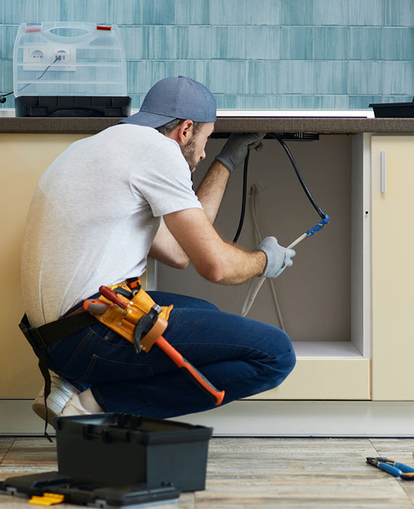 Técnico de fontanería revisando tuberías para mantenimiento preventivo en instalaciones residenciales.