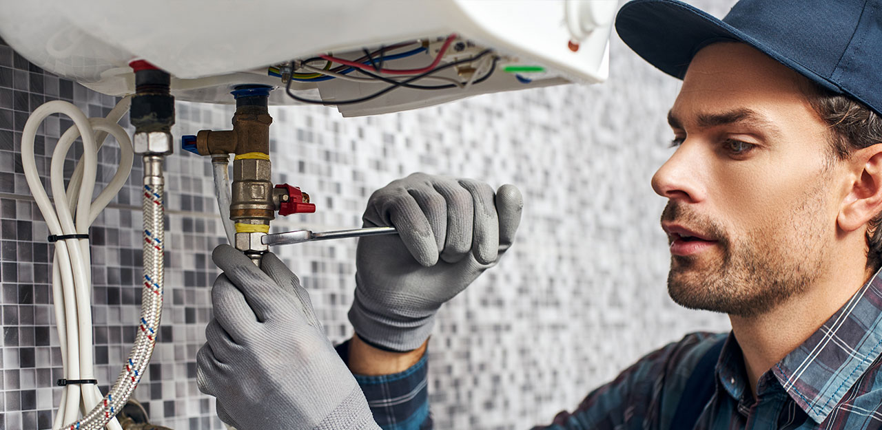 Técnico instalando un sistema de calefacción eléctrica con llave inglesa en mano.