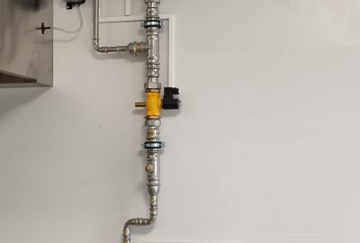 Detalle de un trabajador instalando equipos de fontanería en un espacio de construcción.